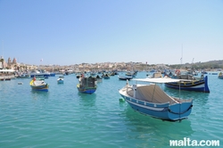 Boats and luzzu in the blue water of Marsaxlokk harbour