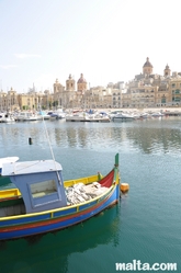 Senglea harbour with a luzzu and the Marine Museum of Victoriosa in the background