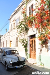 Old car in front of a house in Gudja