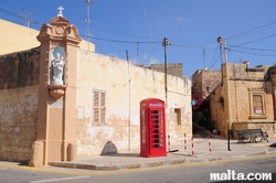 Old phone box and statue in the street of Gudja