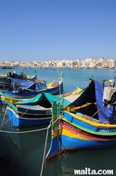 Traditional Maltese luzzu onshore of the Marsaxlokk Bay